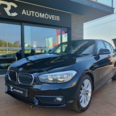 Carro BMW preto em frente a loja RC Automóveis com piso de madeira