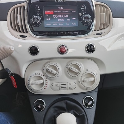 Painel de controlo de carro com rádio digital, botões de ar condicionado e alavanca de mudanças branca