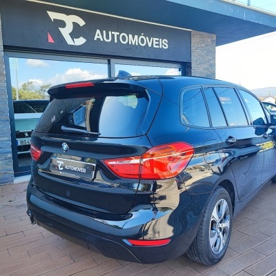 Carro BMW preto carrinha numa área exterior coberta com sinal 'RC AUTOMÓVEIS'