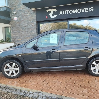 Carro cinza metálico cinco portas junto a loja RC AUTOMÓVEIS