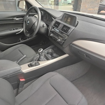 Interior de automóvel BMW em preto e cinza escuro com volante em pele e comandos na consola central.
