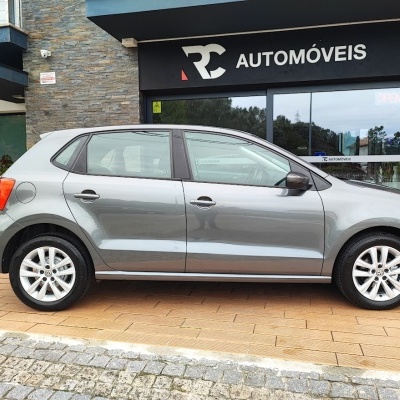 Carro cinzento metálico de cinco portas em frente a loja RC Automóveis