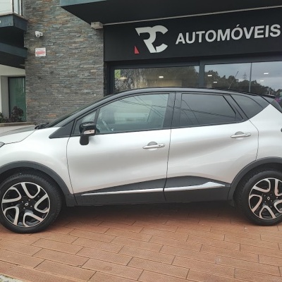 Carro SUV prateado com tejadilho preto em frente a loja AUTOMÓVEIS