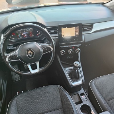 Interior de carro Renault com volante, painel digital, ecrã tátil e assentos em tecido cinzento