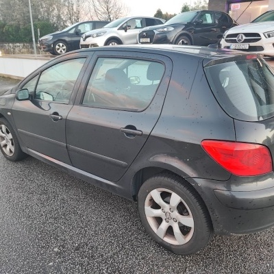 Carro Peugeot preto de cinco portas estacionado na rua
