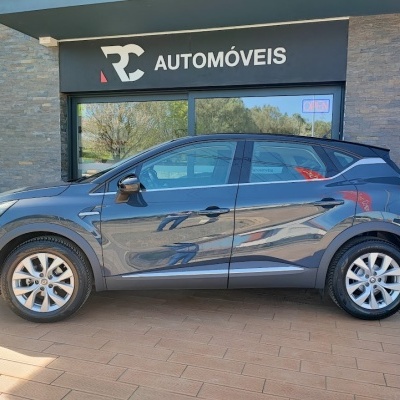 SUV cinza metálico estacionado em frente a loja RC AUTOMÓVEIS com vidro reflexivo