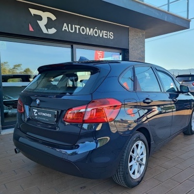 Carro BMW preto estacionado frente a loja RC AUTOMÓVEIS em dia ensolarado