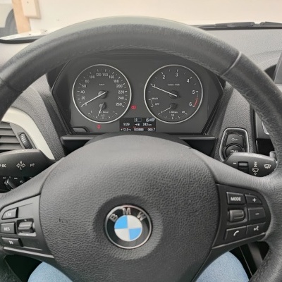 Volante preto em couro com logótipo BMW e painel de instrumentos com velocímetro e conta-rotações