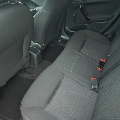 Banco traseiro de carro em tecido preto com costura branca e cintos de segurança vermelhos