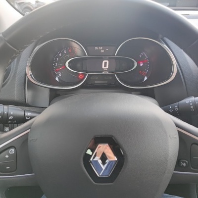 Volante de carro preto com mostrador digital de velocidade e indicadores analógicos ao redor.