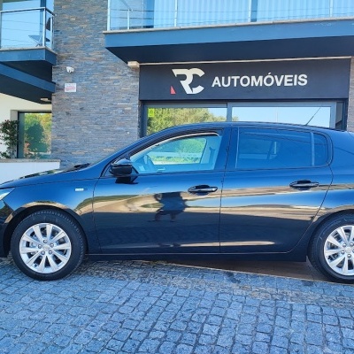 Carro preto estacionado frente a edifício 'RC AUTOMÓVEIS'