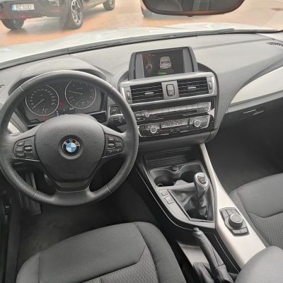 Interior de carro BMW com volante, painel de instrumentos e consola central com ecrã e comandos