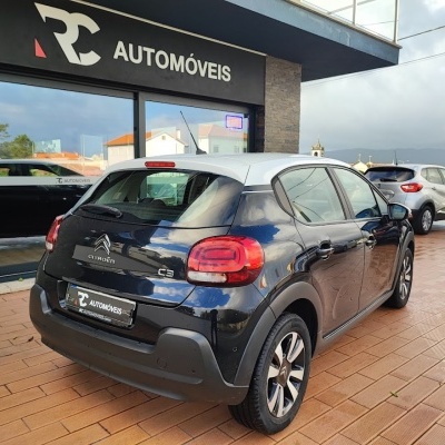 Carro Citroën C3 preto com tejadilho branco em frente à loja RC AUTOMÓVEIS