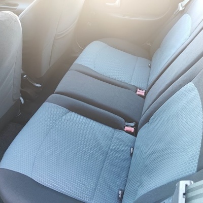 Banco traseiro de carro com estofos azuis e cinzentos e cintos de segurança