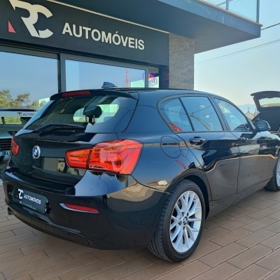 Carro BMW preto estacionado em frente a loja RC AUTOMÓVEIS