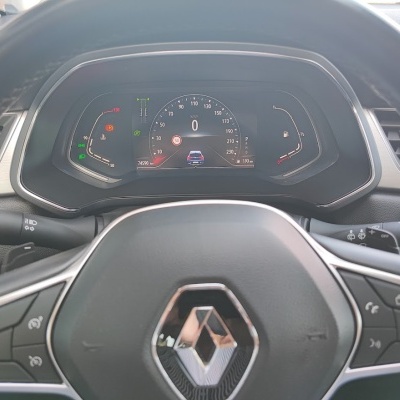 Painel de instrumentos digital de um carro Renault com volante preto de couro e vários botões de controlo.