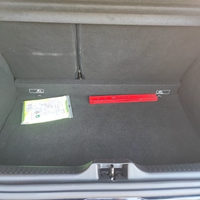 Porta malas de carro com revestimento cinzento escuro e dois objetos no interior