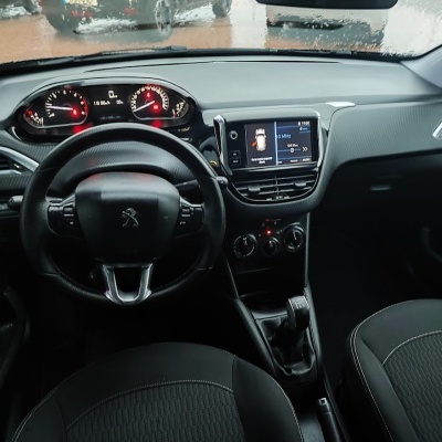 Interior de carro Peugeot com volante em pele e ecrã do rádio em frequência 104 MHz