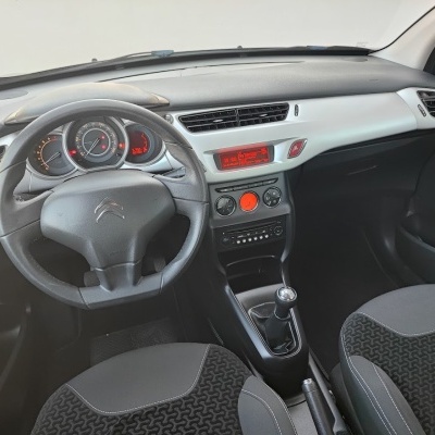 Interior de carro Citroën, volante, painel e bancos em tecido preto com padrão.