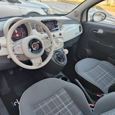 Interior de automóvel Fiat 500 com volante bege e bancos cinzentos