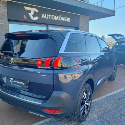 Carro SUV Peugeot azul escuro com vidros escurecidos perante loja RC AUTOMÓVEIS.