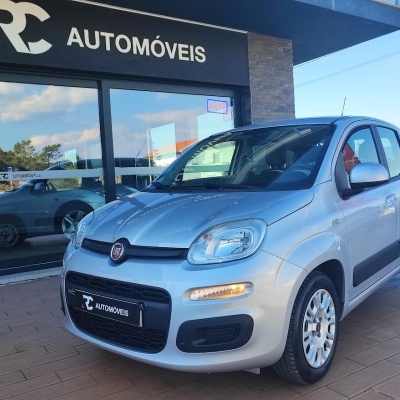 Carro Fiat cinza prata estacionado diante de loja RC AUTOMÓVEIS