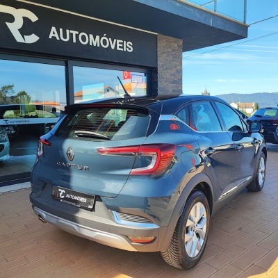 Carro cinzento Renault Captur estacionado em frente a loja RC AUTOMÓVEIS com vidro reflexivo