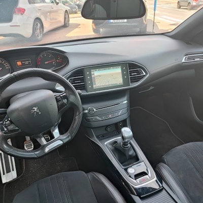Interior de carro Peugeot com volante em couro preto e sistema de navegação no ecrã central