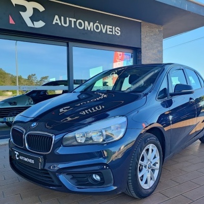 Carro BMW azul escuro ao lado de loja RC AUTOMÓVEIS