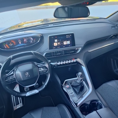 Interior de automóvel Peugeot com volante em couro preto, painel digital e ecrã central tátil.
