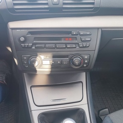 Painel frontal de carro BMW com rádio, comandos de climatização e manípulo de caixa manual.