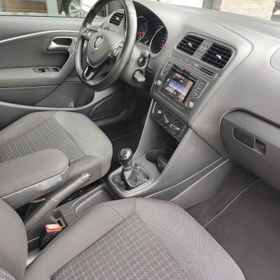 Interior de carro com volante em couro, bancos cinza com padrão quadriculado, painel central com ecrã e caixa de câmbio manual