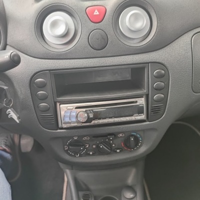 Painel frontal do interior de um carro com rádio e controlos de ar condicionado.
