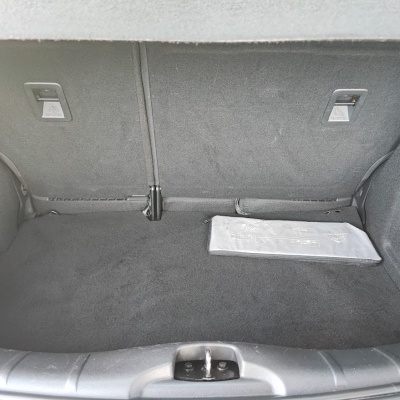 Interior de mala de carro cinza com bolsa branca contendo símbolos