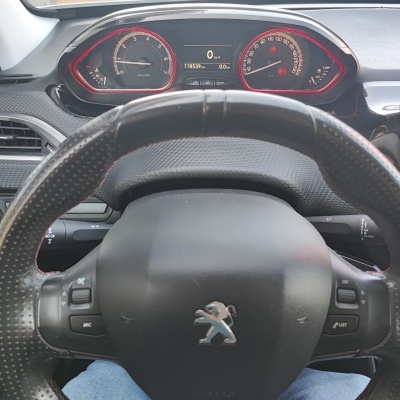 Volante preto em couro com painel de instrumentos Peugeot em carro.