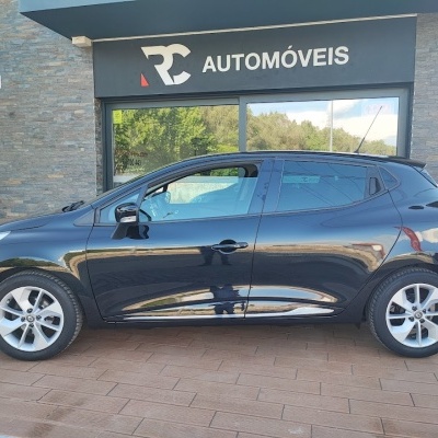 Carro compacto preto estacionado em frente à loja RC AUTOMÓVEIS.