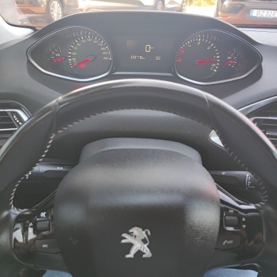 Volante de carro preto com painel de instrumentos e logotipo Peugeot