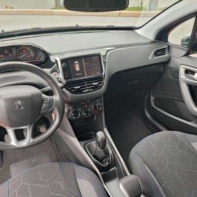 Vista interior do carro Peugeot mostrando volante, bancos, painel e ecrã central