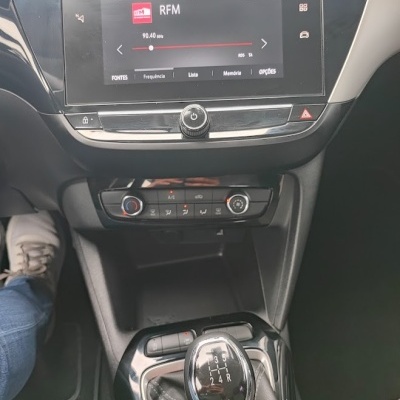 Painel multimedia de carro com ecrã digital a mostrar rádio RFM e manípulo da caixa de velocidades manual