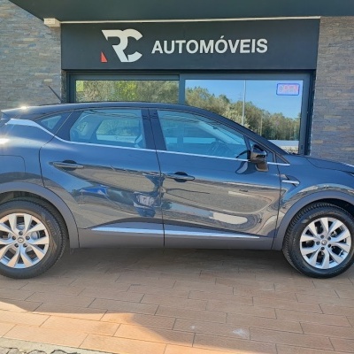 Automóvel cinzento escuro estacionado em frente a loja RC AUTOMÓVEIS com placa OPEN