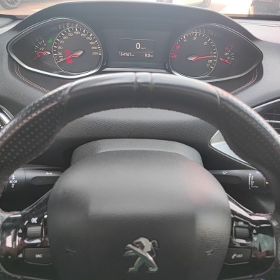 Painel e volante de carro Peugeot preto com mostradores analógicos e digitais.