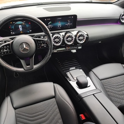 Interior de carro Mercedes com volante em couro preto e painel digital.