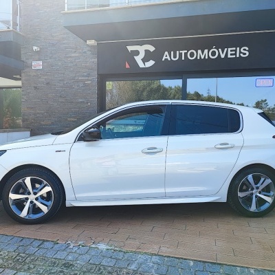 Carro branco estacionado em frente a loja RC AUTOMÓVEIS