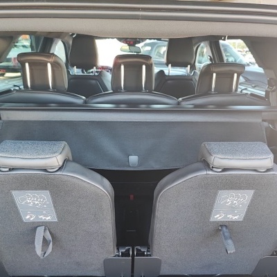 Interior de automóvel com bancos traseiros rebatidos em couro preto e cinza.