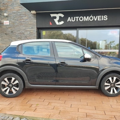 Automóvel Citroën preto com tejadilho branco em frente a loja RC AUTOMÓVEIS