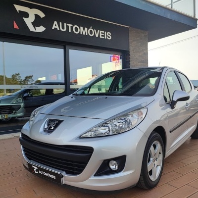 Carro Peugeot prateado em frente a loja RC AUTOMÓVEIS