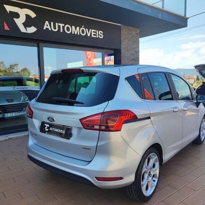 Carro Ford branco estacionado em loja RC AUTOMÓVEIS com outra viatura branca ao fundo