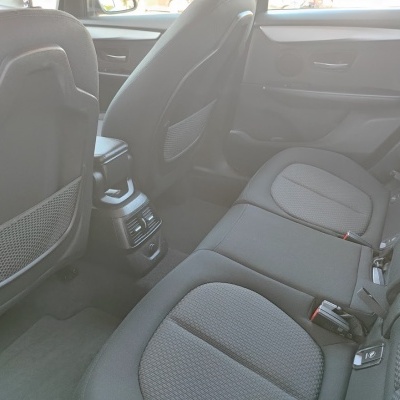 Interior traseiro de carro com bancos cinza escuro em tecido e saídas de ar no console central.