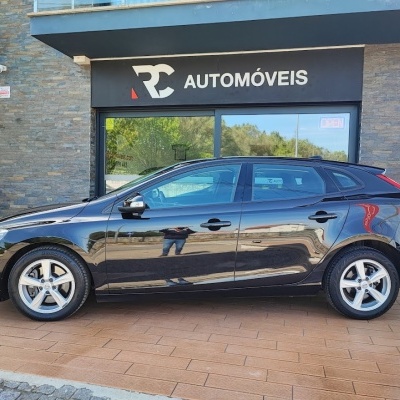 Carro preto com jantes prateadas estacionado frente à loja RC Automóveis
