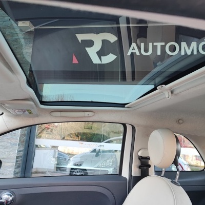 Interior de carro com assento branco, teto de vidro e janela lateral com puxador cromado